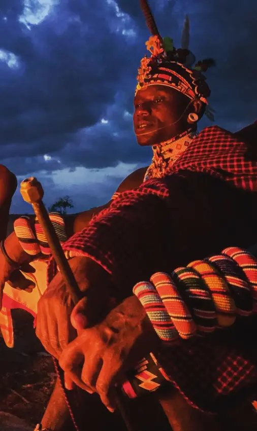 Two people in traditional dress posing together outdoors, Elephant Watch Camp, Samburu Reserve, Kenya