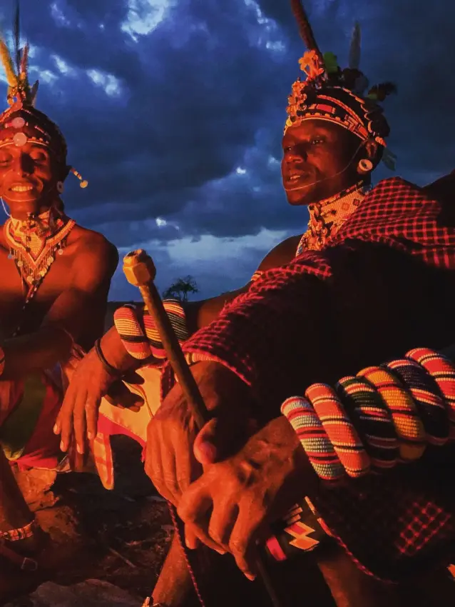 Two people in traditional dress posing together outdoors, Elephant Watch Camp, Samburu Reserve, Kenya