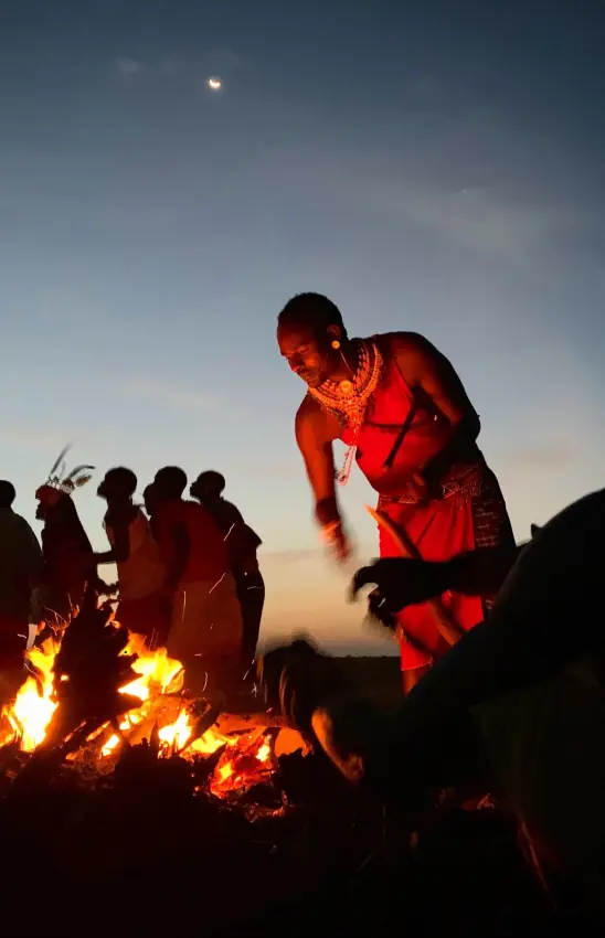 Maasai warriors gathered around evening campfire under moonlight, Elephant Watch Camp, Samburu Reserve, Kenya