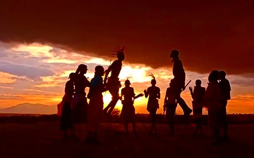 Silhouetted children playing at sunset over savanna, Elephant Watch Camp, Samburu Reserve, Kenya