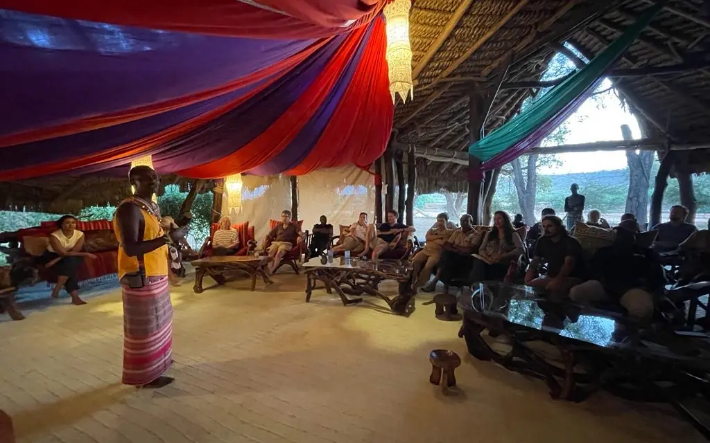 Open-air lodge interior with guests seated on floor cushions, Elephant Watch Camp, Samburu Reserve, Kenya