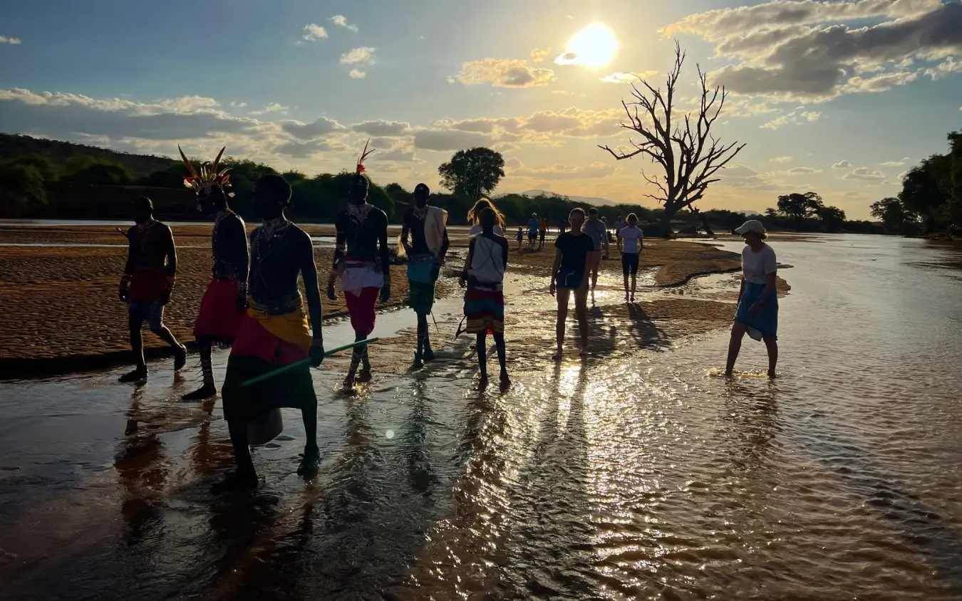 Group wading in river at golden hour sunset, Elephant Watch Camp, Samburu Reserve, Kenya