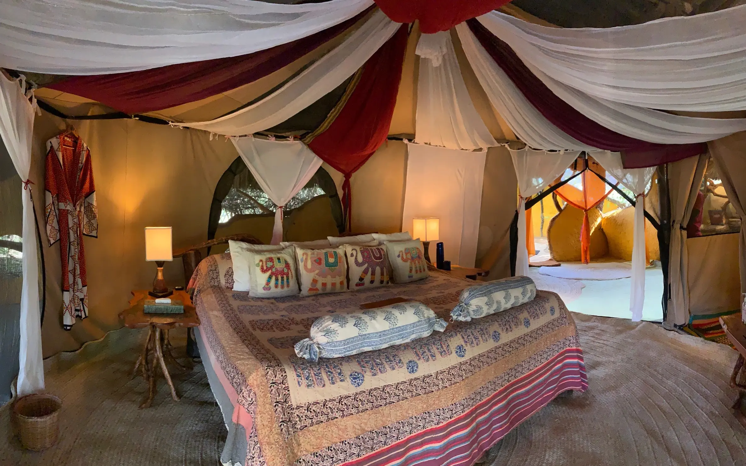 Luxurious tent bedroom with draped fabric canopy and warm lighting, Elephant Watch Camp, Samburu Reserve, Kenya