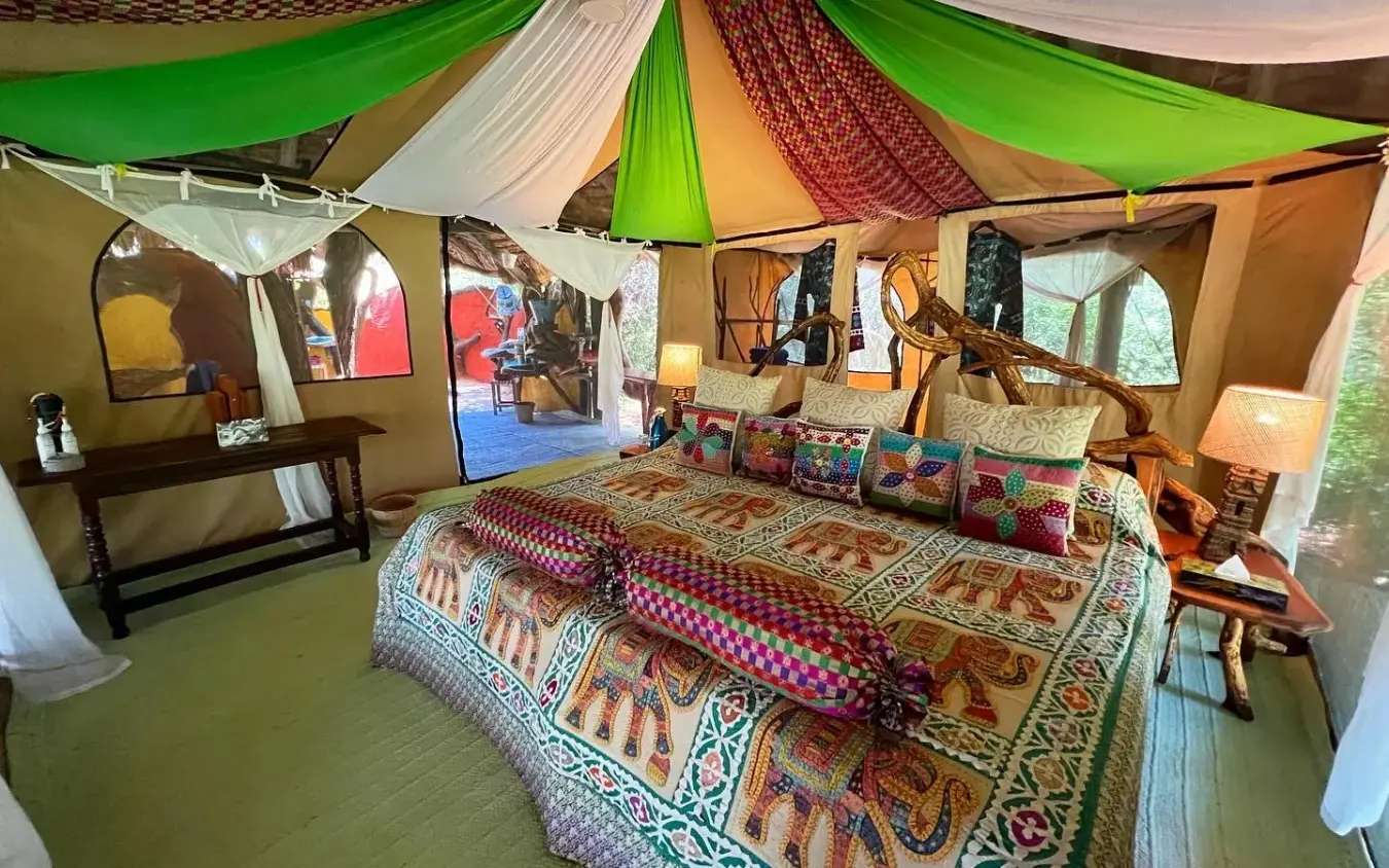 Spacious canvas tent interior with colorful patterned bedding and furnishings, Elephant Watch Camp, Samburu Reserve, Kenya