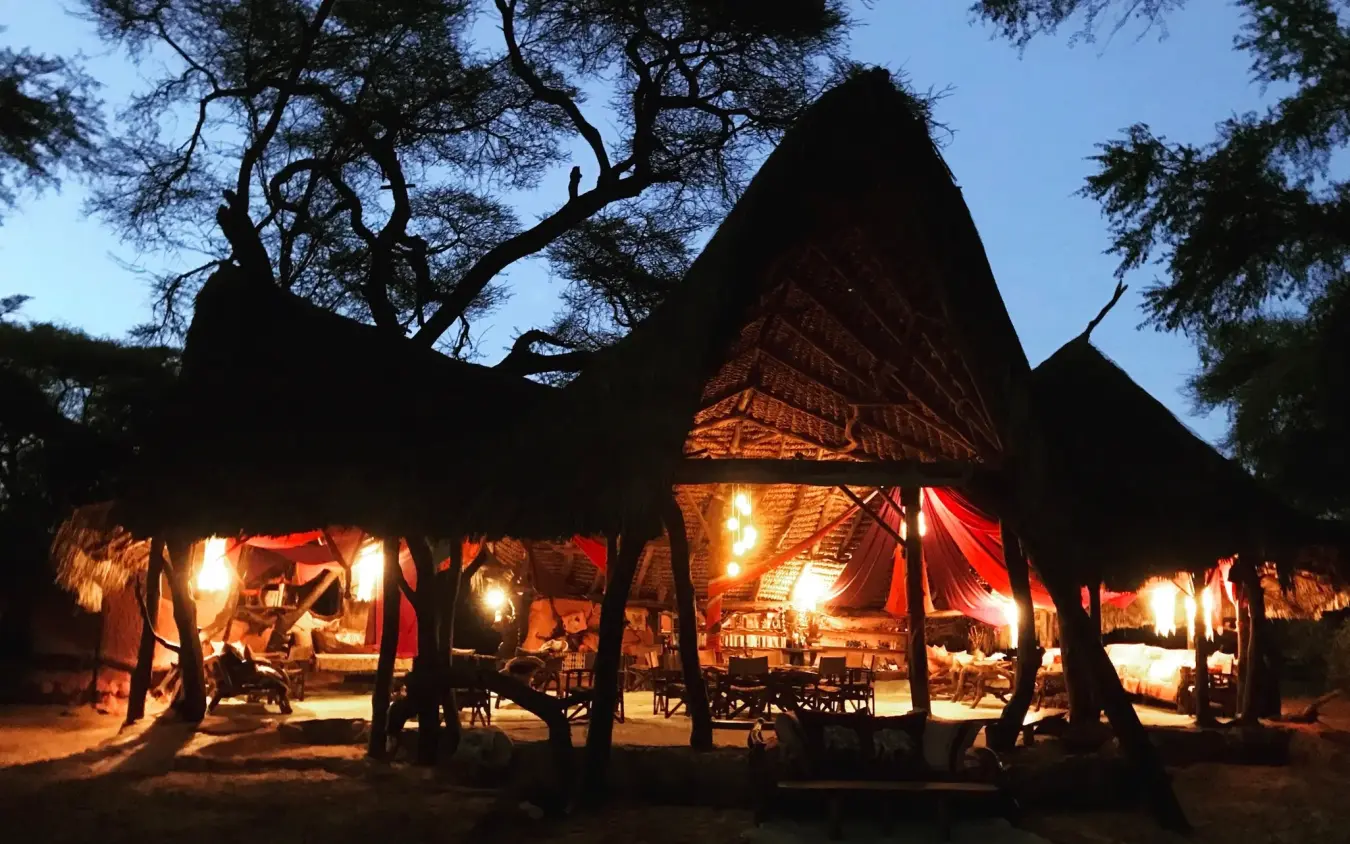 Illuminated dining pavilions beneath acacia trees at dusk, Elephant Watch Camp, Samburu Reserve, Kenya