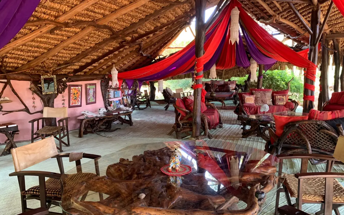 Open-air lounge with red fabric draping and wooden furniture, Elephant Watch Camp, Samburu Reserve, Kenya