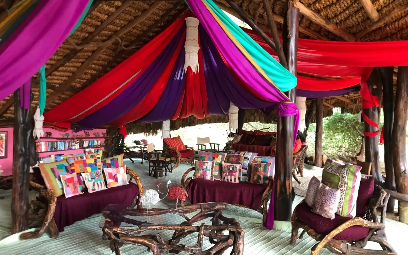 Colorful draped lounge area with wooden furniture and artwork, Elephant Watch Camp, Samburu Reserve, Kenya
