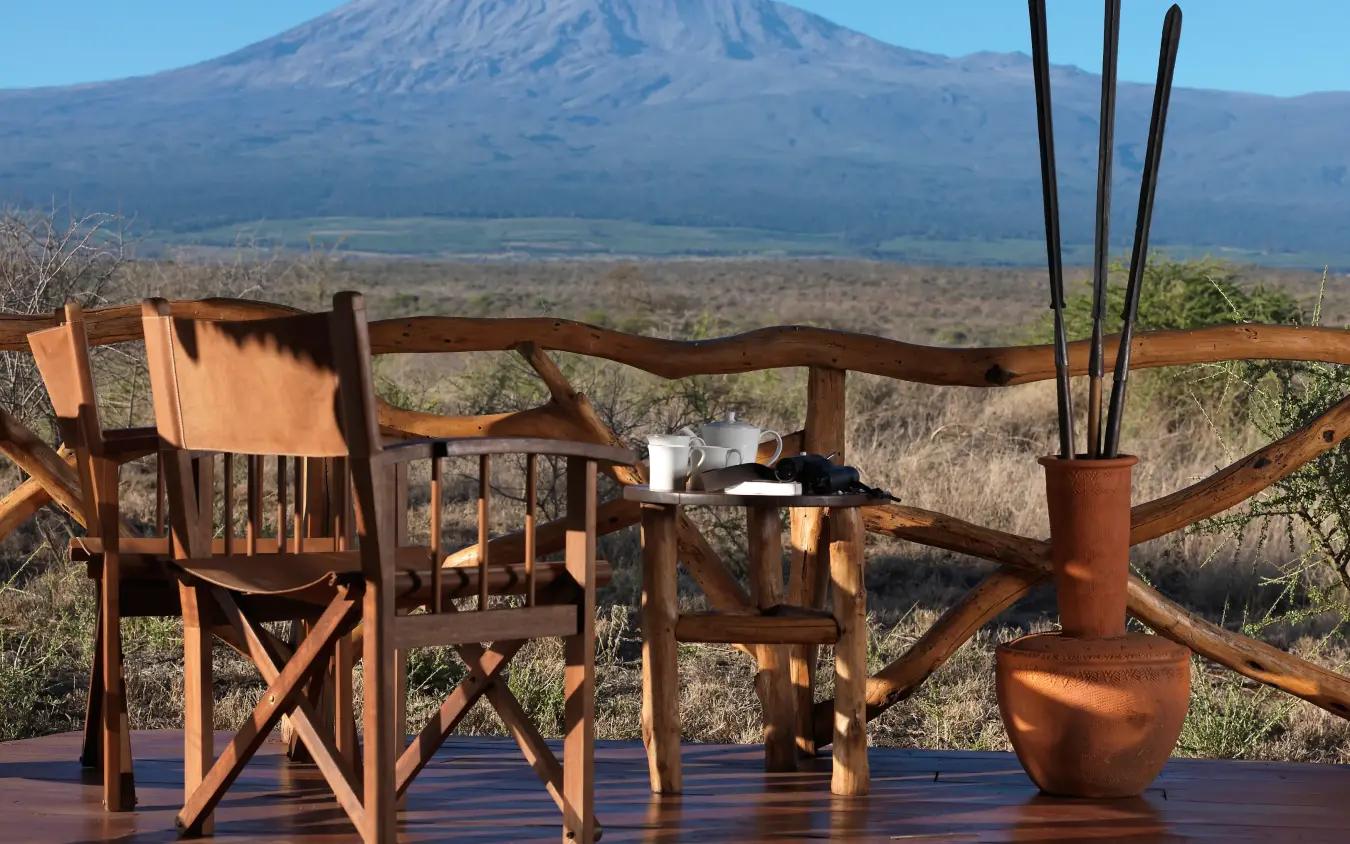 Wooden deck furniture overlooking savanna and snow-capped mountain, Elerai, Amboseli and Chyulu Hills, Kenya