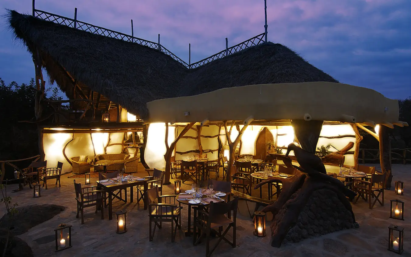 Open-air dining pavilion illuminated at dusk with tables set, Elerai, Amboseli and Chyulu Hills, Kenya