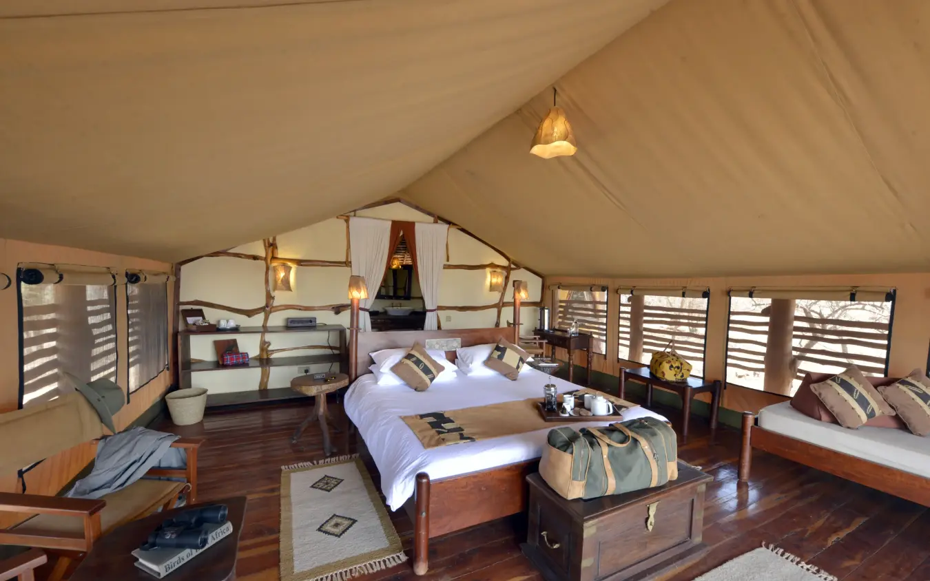 Spacious safari tent bedroom with wooden furnishings and natural light, Elerai, Amboseli and Chyulu Hills, Kenya