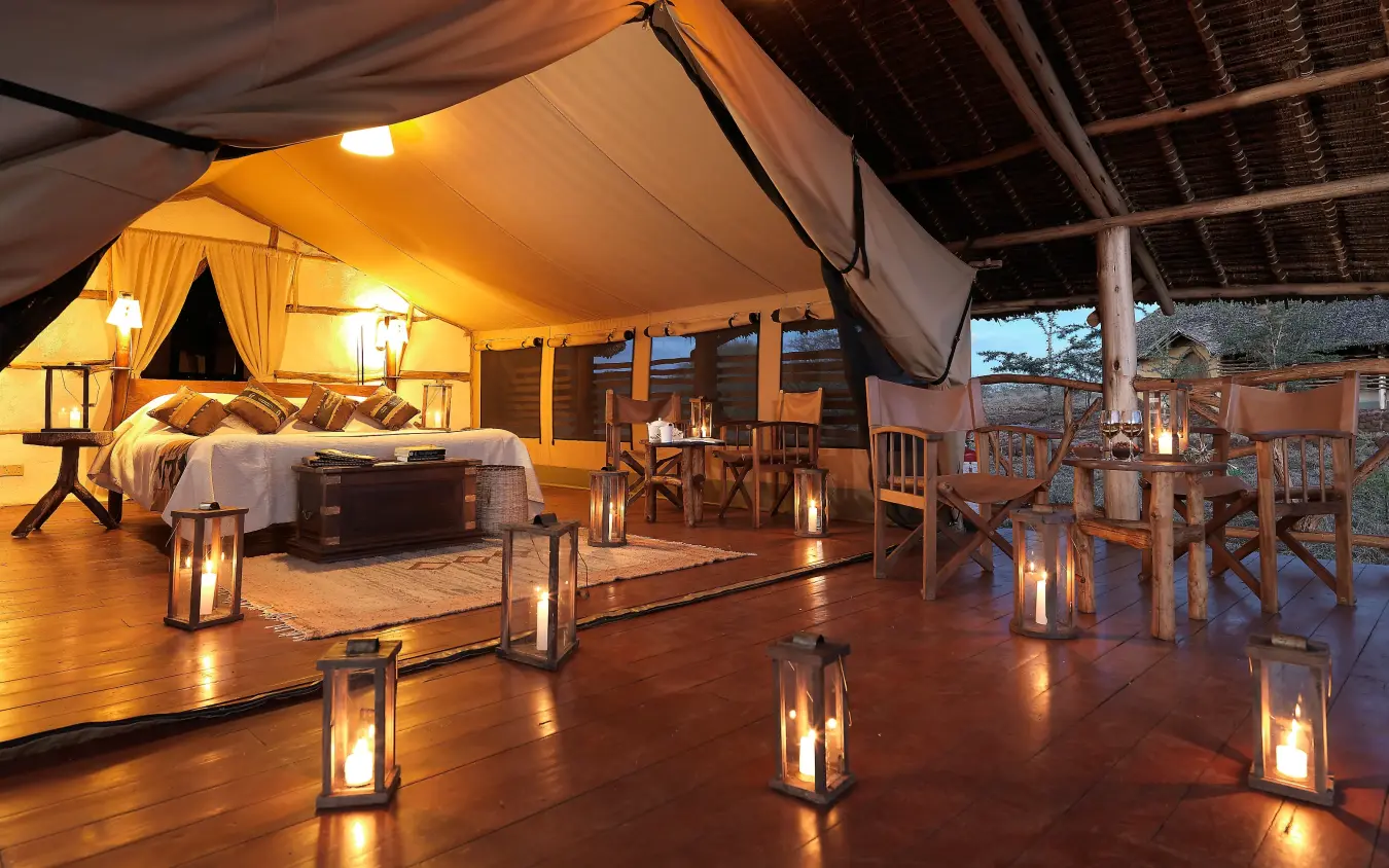Luxury tent bedroom with deck seating area at dusk, Elerai, Amboseli and Chyulu Hills, Kenya
