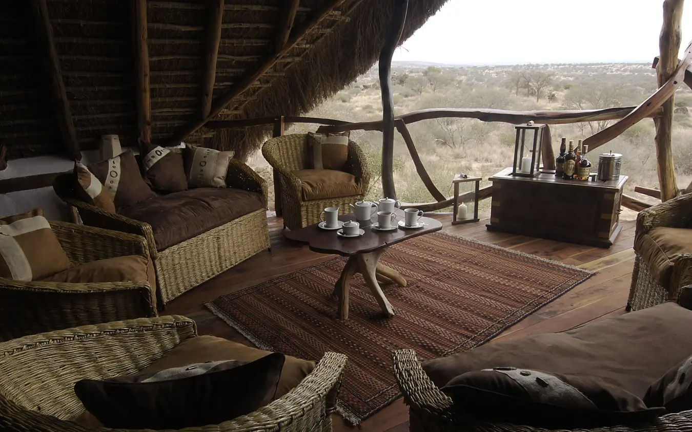 Thatched lounge area with wicker furniture overlooking savanna, Elerai, Amboseli and Chyulu Hills, Kenya