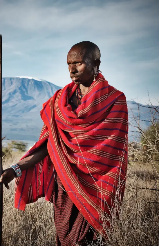 Maasai warrior in red shawl holding spear with mountain, Elerai, Amboseli and Chyulu Hills, Kenya