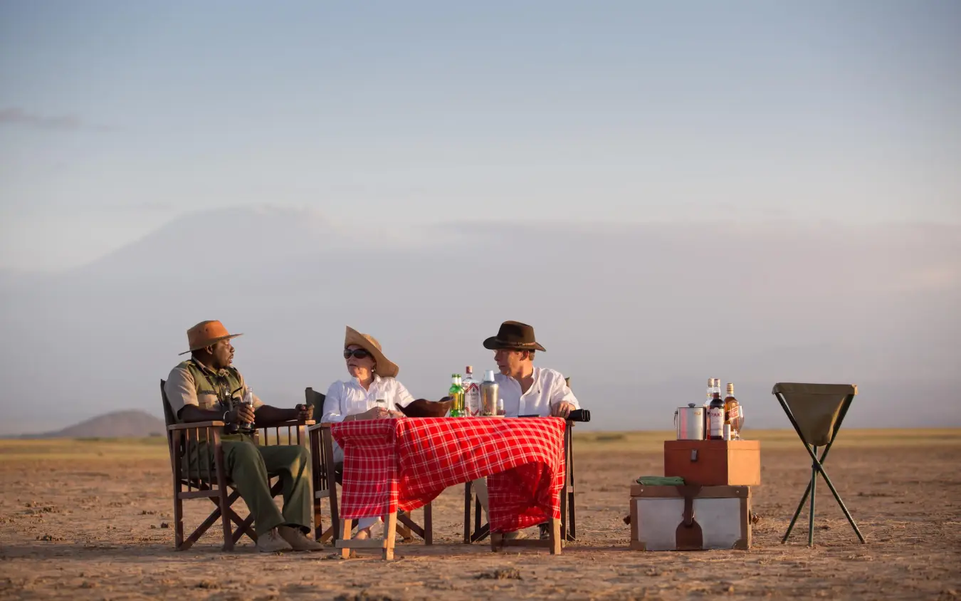 Guests dining at table in open savanna landscape, Tortilis Camp, Amboseli and Chyulu Hills, Kenya