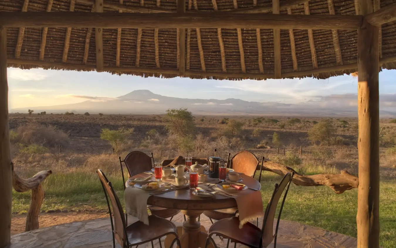 Dining setup on deck overlooking African savanna and distant mountain, Tortilis Camp, Amboseli and Chyulu Hills, Kenya