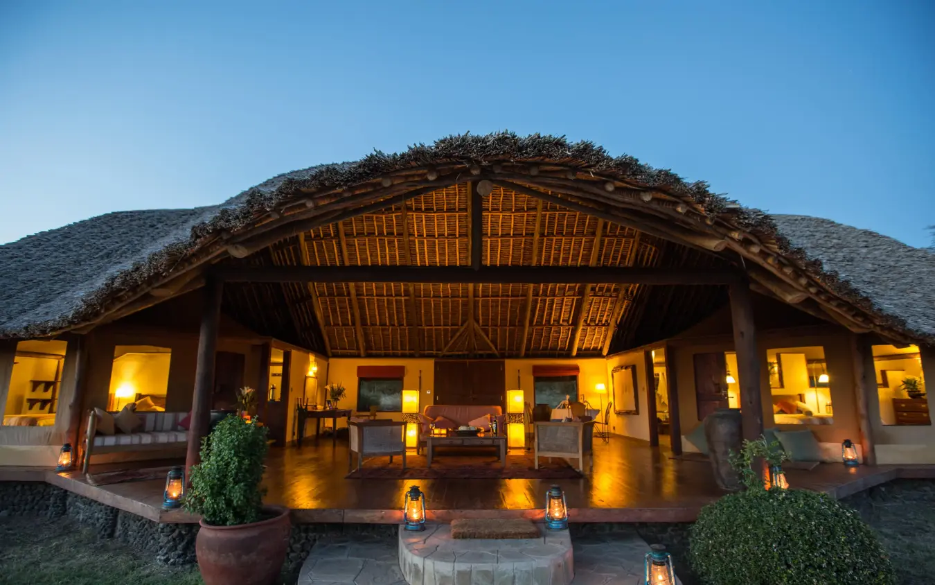 Illuminated lodge building with thatched roof at dusk, Tortilis Camp, Amboseli and Chyulu Hills, Kenya
