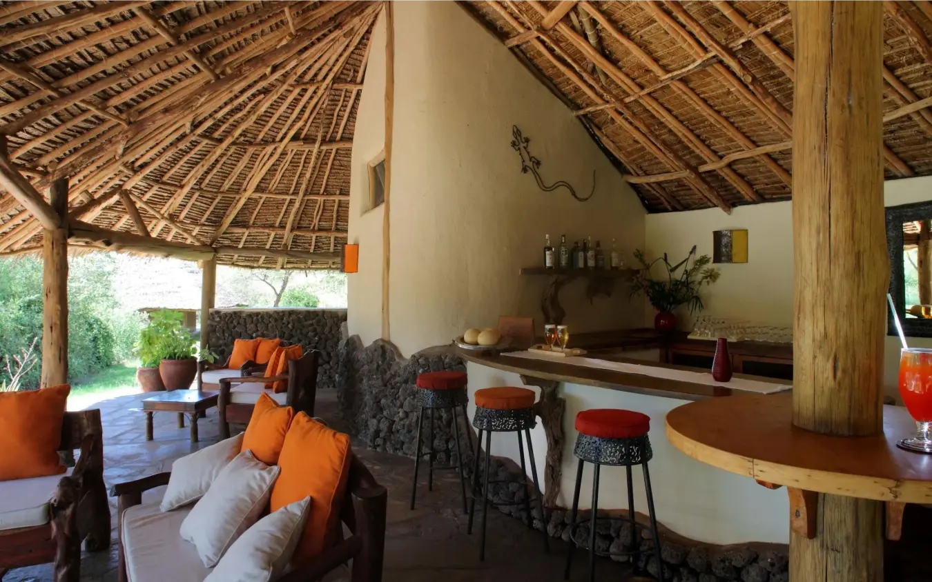 Open-air lounge with thatched roof and orange accents, Tortilis Camp, Amboseli and Chyulu Hills, Kenya