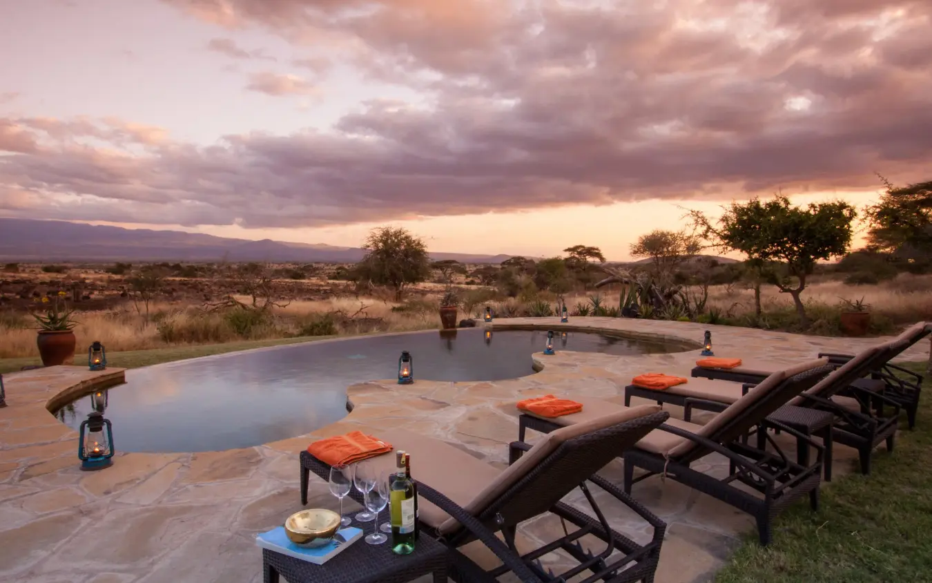 Infinity pool at sunset with savanna landscape beyond, Tortilis Camp, Amboseli and Chyulu Hills, Kenya