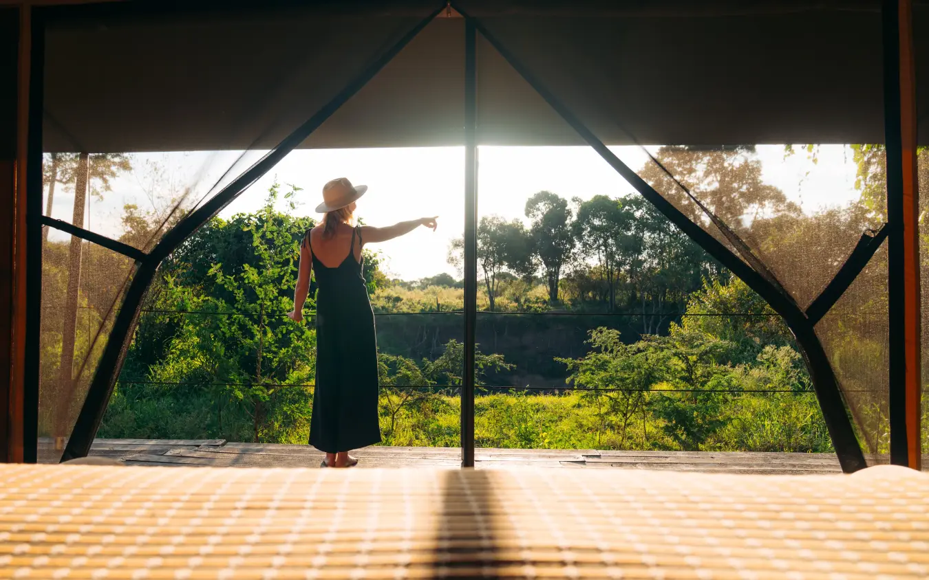 Woman standing on wooden deck overlooking savanna landscape, Emboo Camp, Maasai Mara, Kenya