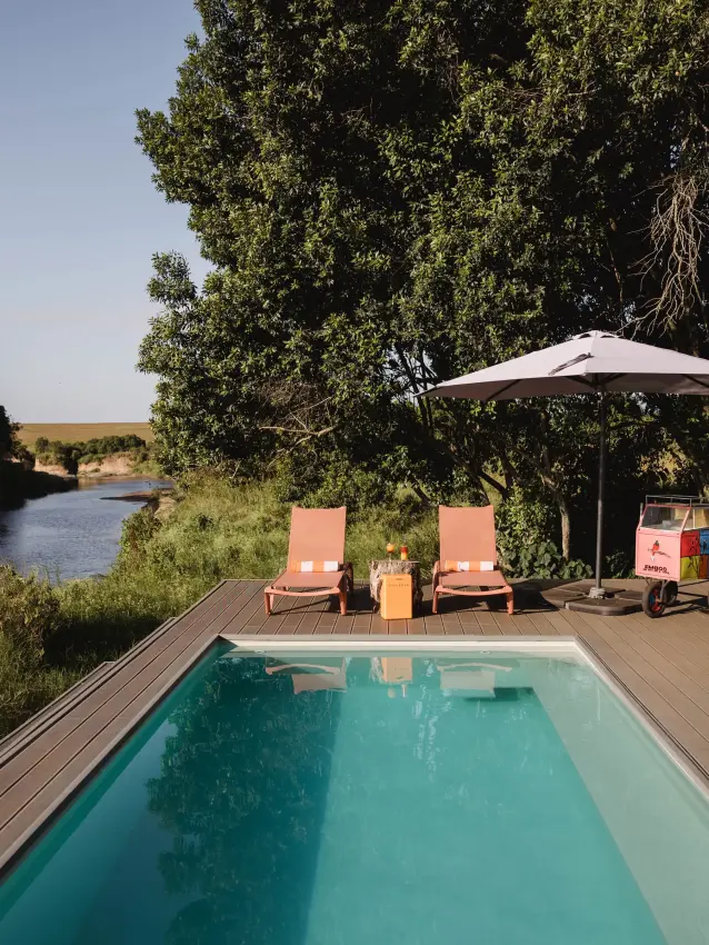 Infinity pool overlooking river with loungers and shade umbrella, Emboo Camp, Maasai Mara, Kenya