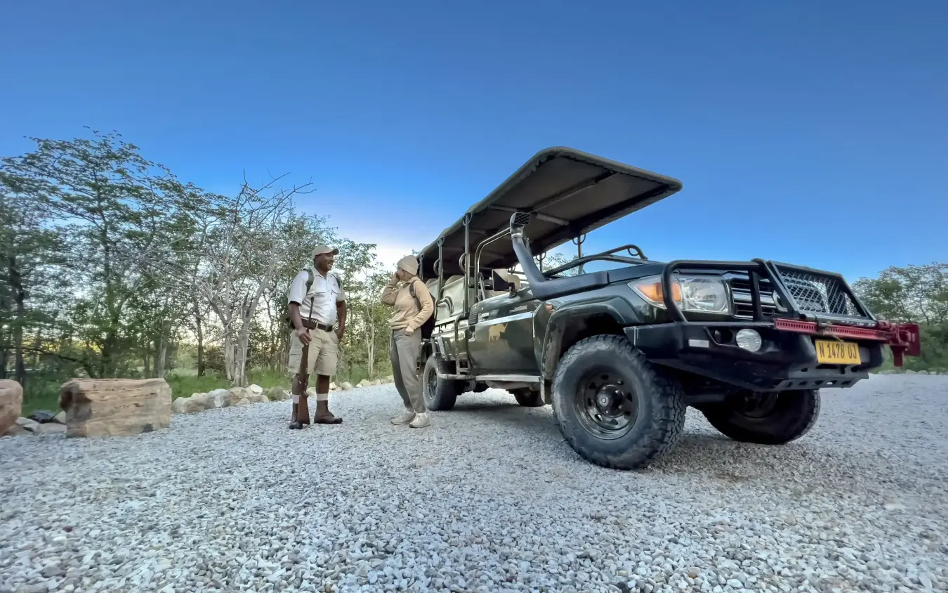 Safari vehicle with guides and open sky landscape, Encounter by Ongava, Etosha National Park, Namibia