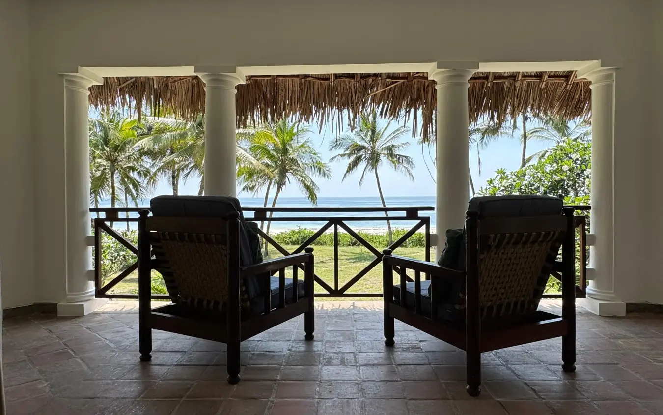 Beachfront lounge with palm trees and ocean view through white columns, Enkare Bofa, Kilifi, Kenya
