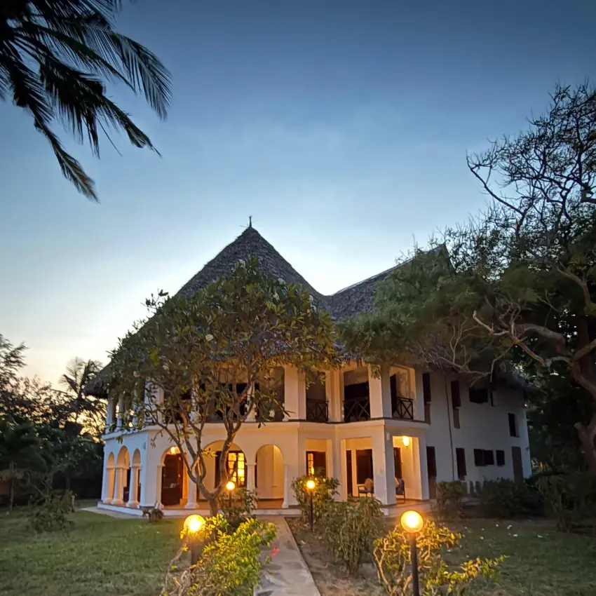 Traditional thatched-roof lodge building with African vegetation and clear sky, Enkare Bofa, Kilifi, Kenya