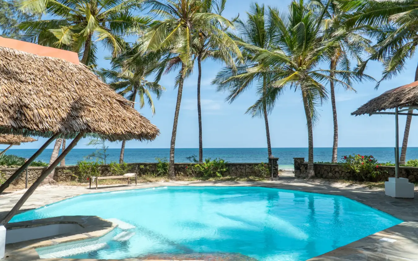 Beachfront swimming pool with thatched umbrellas and palm trees, Enkare Bofa, Kilifi, Kenya