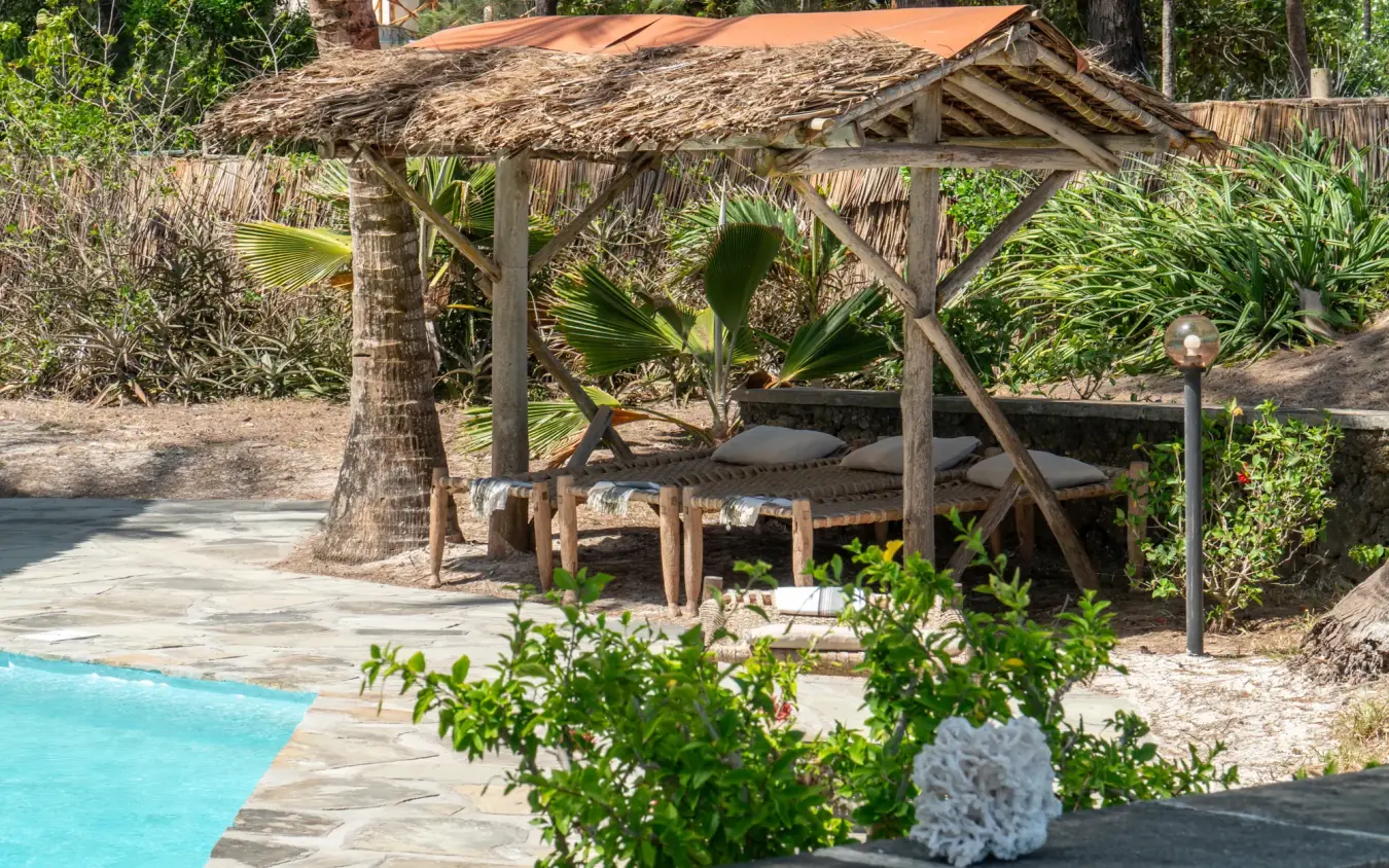 Thatched poolside bungalow with wooden deck and tropical vegetation, Enkare Bofa, Kilifi, Kenya