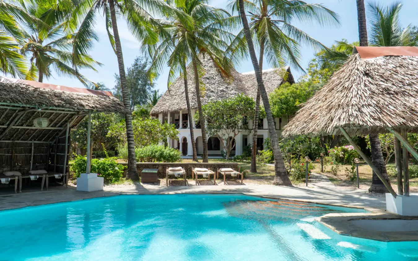 Swimming pool with thatched structures and palm trees at tropical resort, Enkare Bofa, Kilifi, Kenya