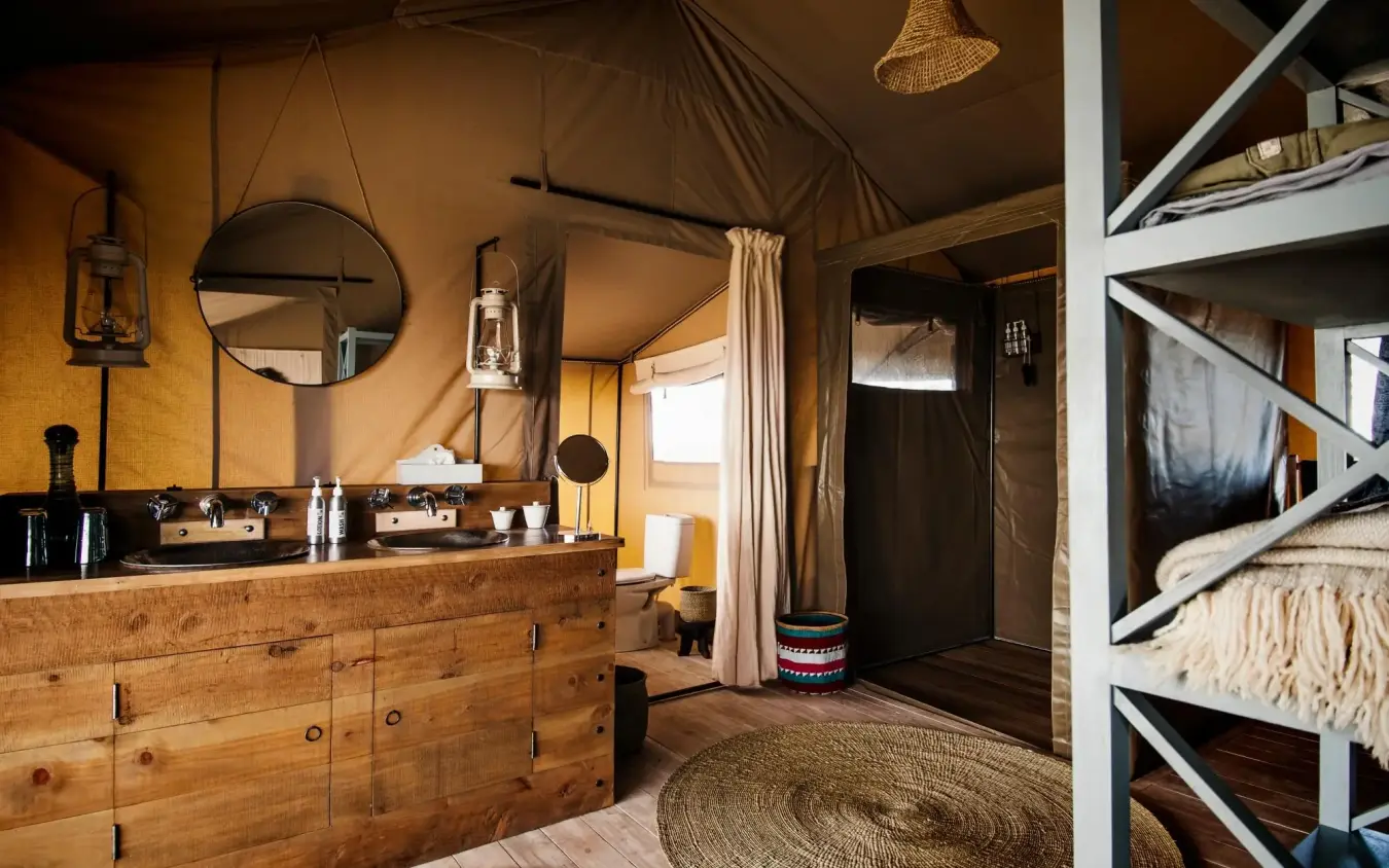 Luxury safari tent interior with wooden vanity and round mirror, Entamanu Camp, Ngorongoro Crater, Tanzania