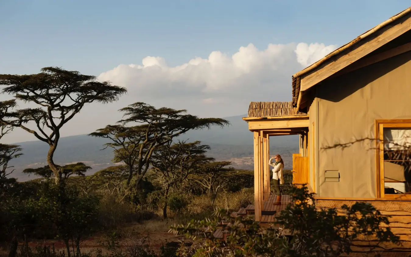 Luxury lodge with guest on wooden deck overlooking acacia trees and valley, Entamanu Private, Ngorongoro Crater, Tanzania