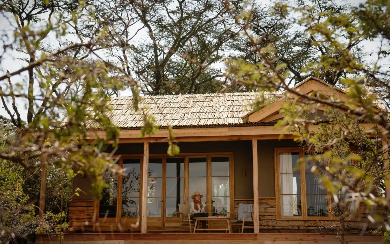 Wooden lodge with covered veranda overlooking dry woodland trees, Entamanu Private, Ngorongoro Crater, Tanzania