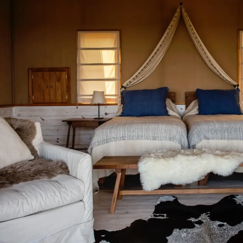 Luxury bedroom with canopy bed and savanna views through large windows, Entamanu Private, Ngorongoro Crater, Tanzania