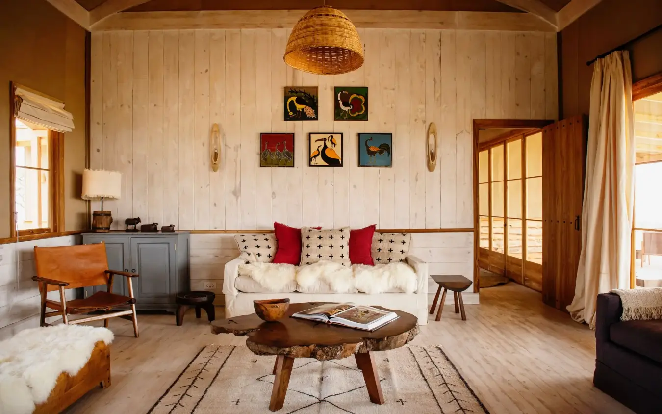 Wooden lodge interior with cream sofa and carved game animal artwork, Entamanu Private, Ngorongoro Crater, Tanzania