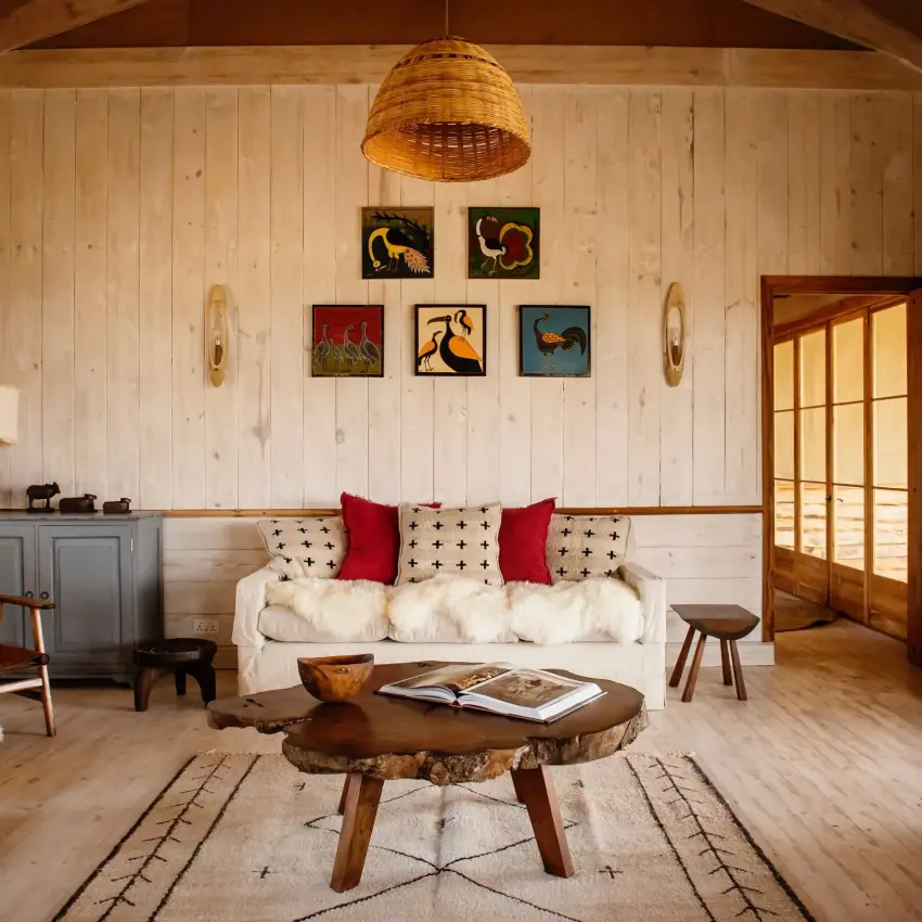 Wooden lodge interior with cream sofa and carved game animal artwork, Entamanu Private, Ngorongoro Crater, Tanzania