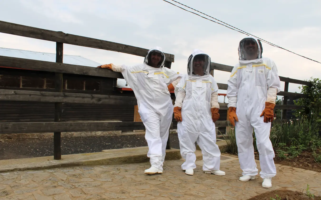 Four beekeepers in protective suits posing together outdoors, Farmhouse Rwanda, Volcanoes National Park, Rwanda