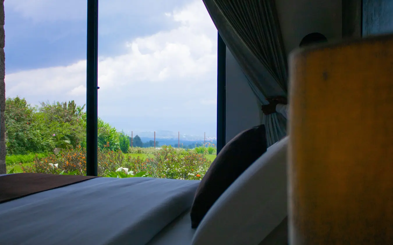Guest room window overlooking green fields and distant mountains, Farmhouse Rwanda, Volcanoes National Park, Rwanda