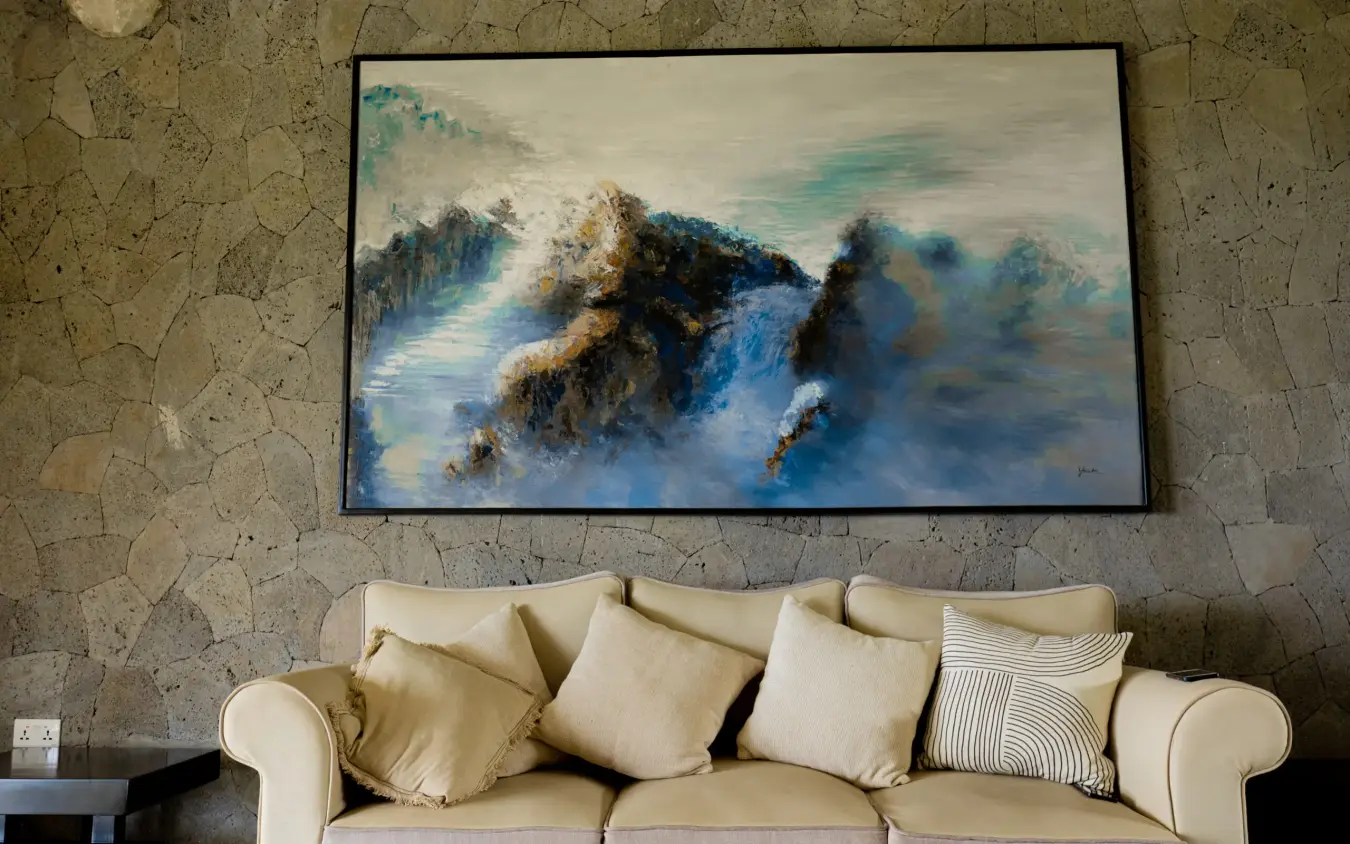 Cream sofa with cushions beneath landscape painting, Farmhouse Rwanda, Volcanoes National Park, Rwanda