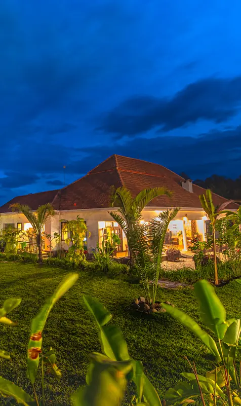 Illuminated lodge buildings at dusk with manicured grounds, Five Volcanoes, Volcanoes National Park, Rwanda