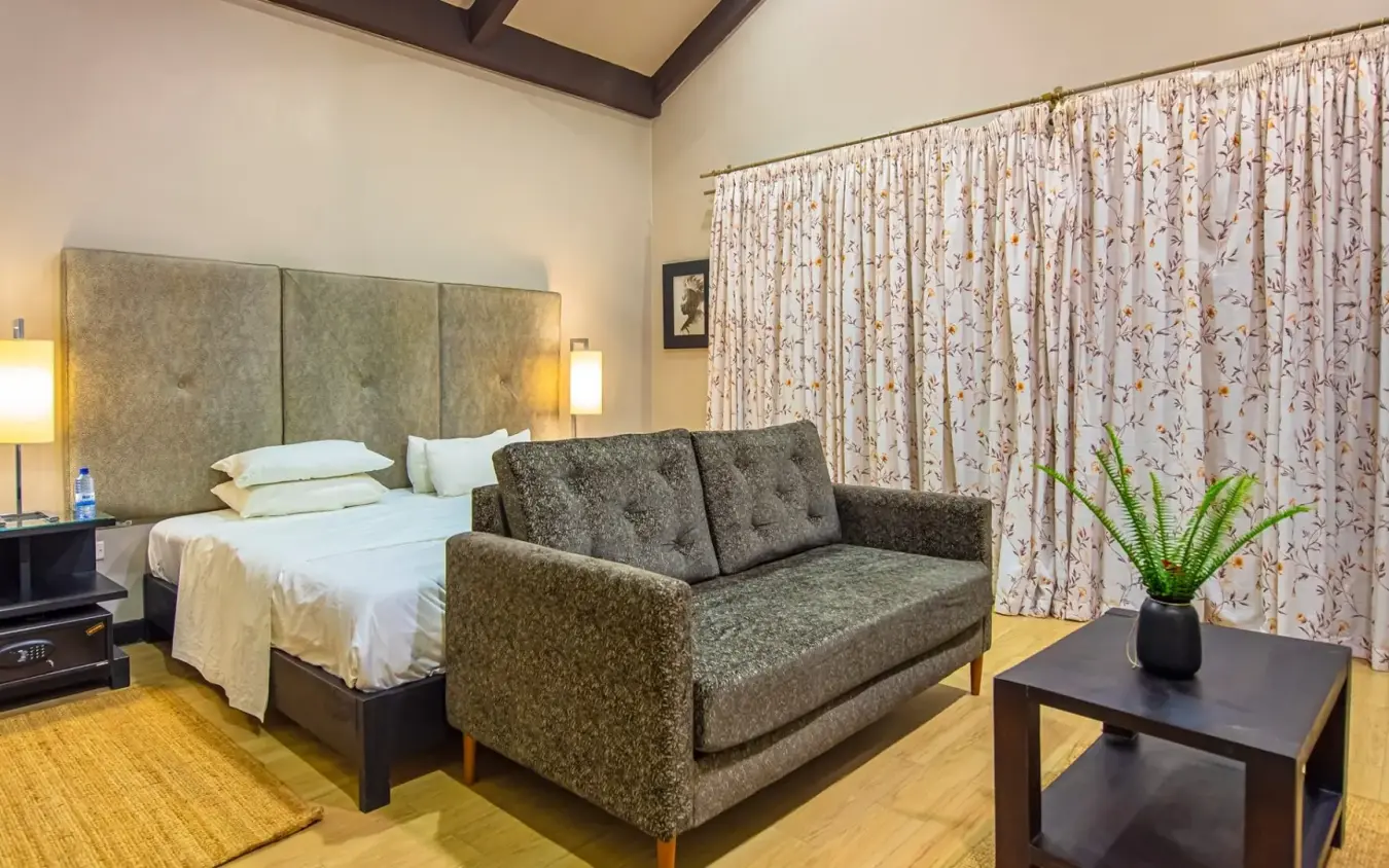 Spacious bedroom with green upholstered headboard and sofa, Five Volcanoes, Volcanoes National Park, Rwanda