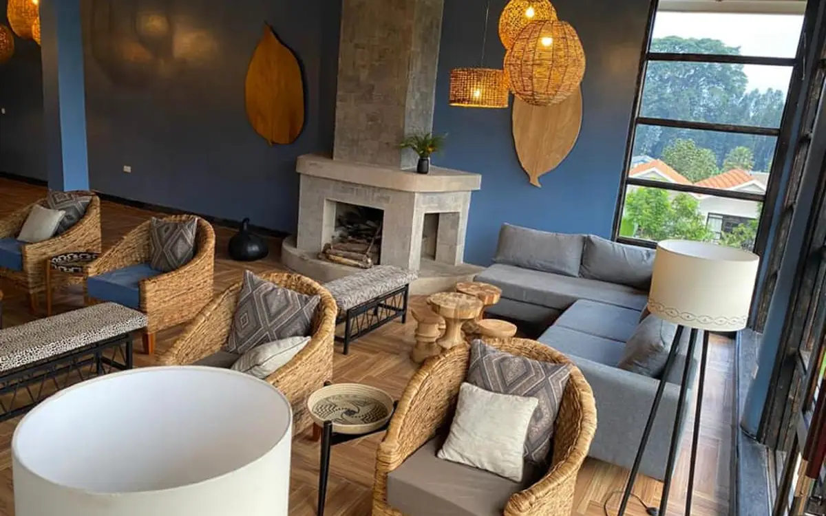 Modern lounge with woven chairs and fireplace overlooking gardens, Five Volcanoes, Volcanoes National Park, Rwanda