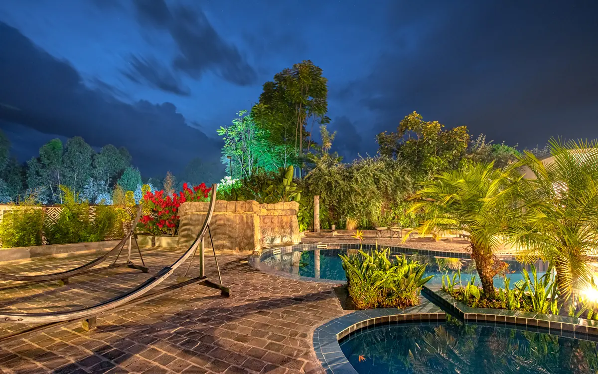 Illuminated resort pool and gardens at twilight with tropical plants, Five Volcanoes, Volcanoes National Park, Rwanda