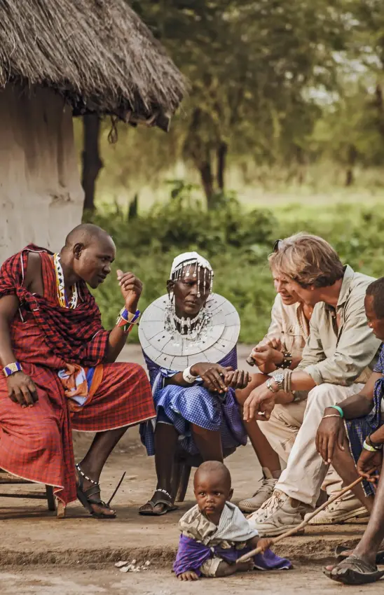 Tourist interacting with local community members outside traditional dwelling, Forest Chem Chem, Lake Manyara, Tanzania