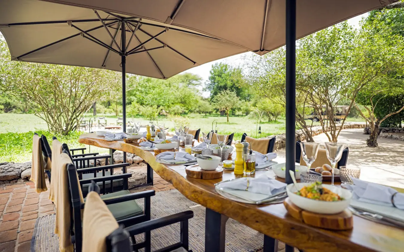 Outdoor dining setup under umbrellas with table settings, Forest Chem Chem, Lake Manyara, Tanzania