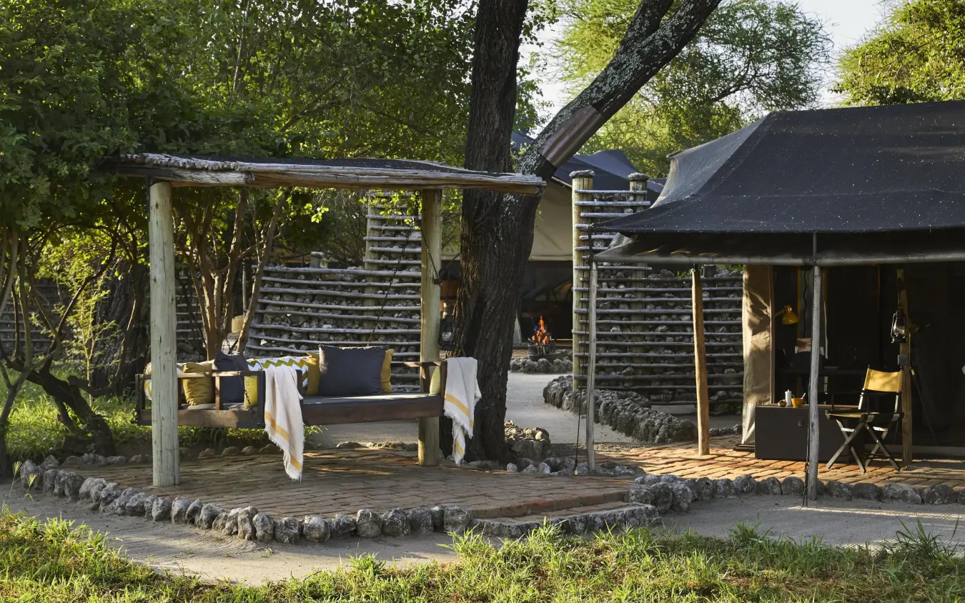 Safari lodge structures with wooden shaded seating areas nestled among trees, Forest Chem Chem, Lake Manyara, Tanzania