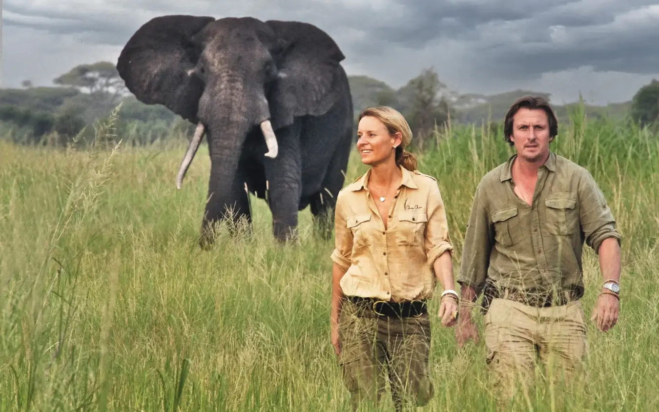 Two guides walking through grassland with elephant behind, Forest Chem Chem, Lake Manyara, Tanzania