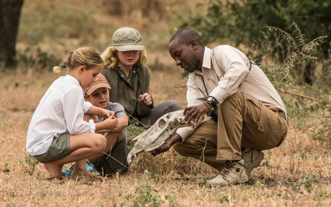 Guide showing children a reptile during nature education, Forest Chem Chem, Lake Manyara, Tanzania