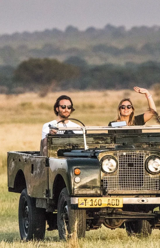 Guests on safari vehicle in open grassland savanna landscape, Forest Chem Chem, Lake Manyara, Tanzania