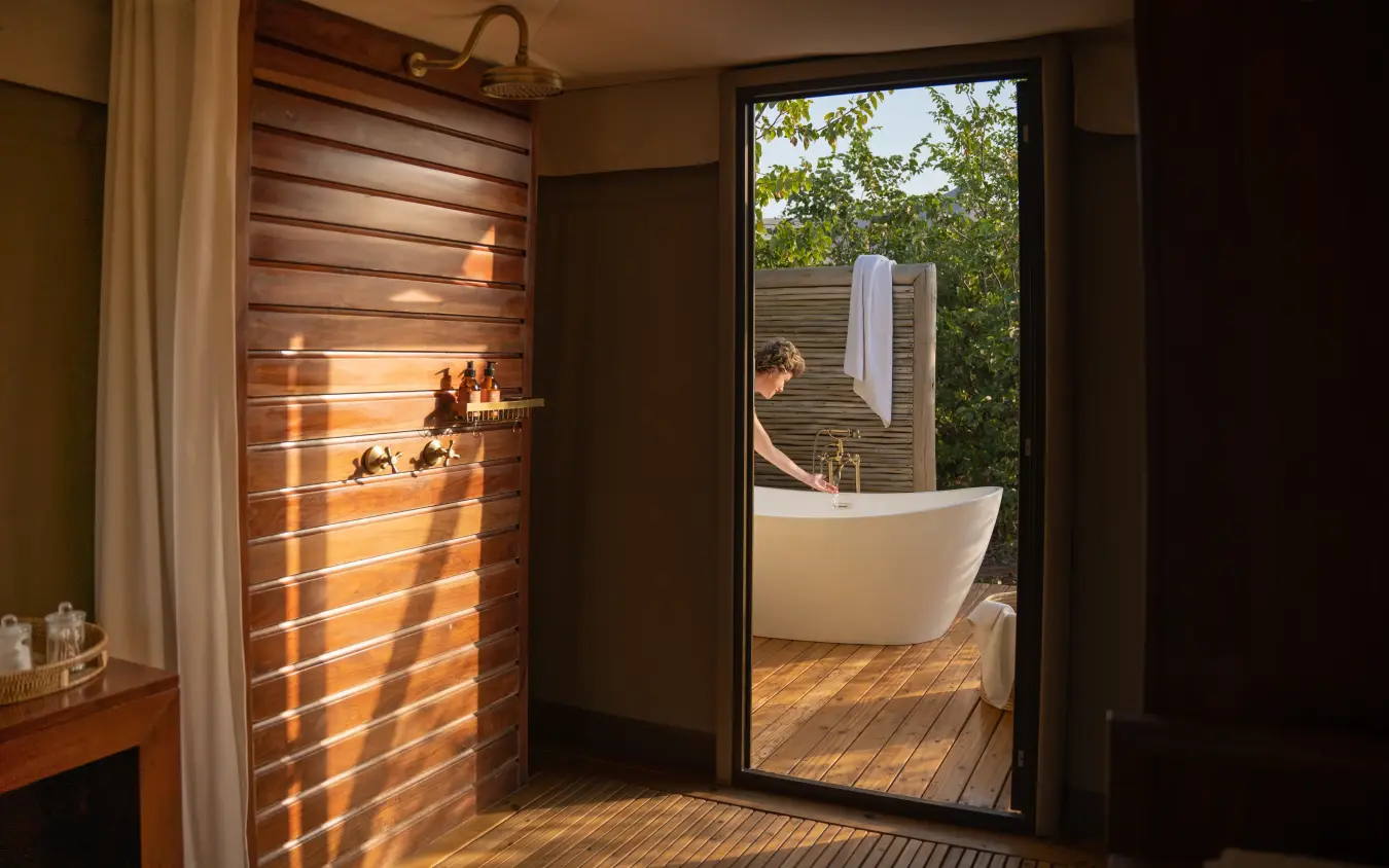 Outdoor bathroom with freestanding tub on wooden deck among trees, Fothergill Island, Matusadona National Park, Zimbabwe